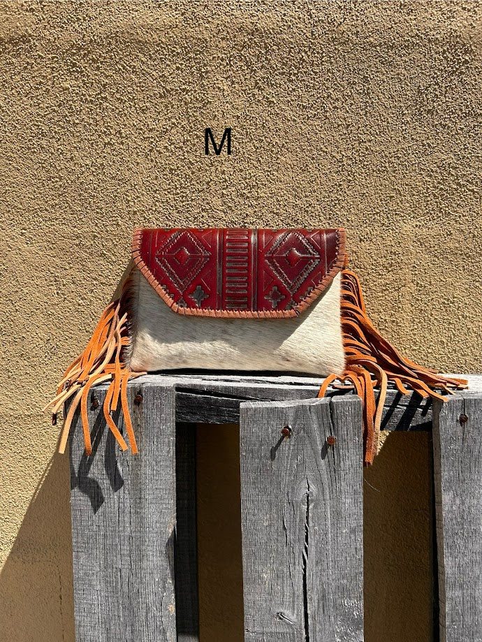 Cowhide purse with Brown leather embossed flap and tassel detail. Has a removable, adjustable shoulder strap and a wristlet strap. Front View M