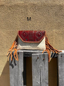 Cowhide purse with Brown leather embossed flap and tassel detail. Has a removable, adjustable shoulder strap and a wristlet strap. Front View M