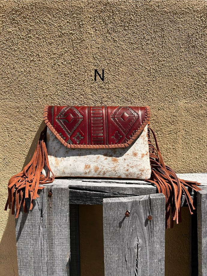 Cowhide purse with Brown leather embossed flap and tassel detail. Has a removable, adjustable shoulder strap and a wristlet strap. Front View N