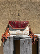 Cowhide purse with Brown leather embossed flap and tassel detail. Has a removable, adjustable shoulder strap and a wristlet strap. Front View N