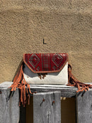 Cowhide purse with Brown leather embossed flap and tassel detail. Has a removable, adjustable shoulder strap and a wristlet strap. Front View L