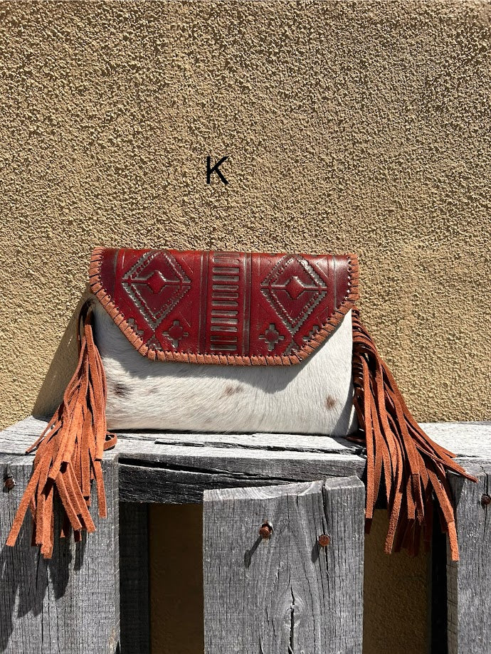 Cowhide purse with Brown leather embossed flap and tassel detail. Has a removable, adjustable shoulder strap and a wristlet strap. Front View K