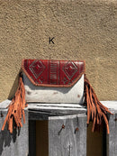 Cowhide purse with Brown leather embossed flap and tassel detail. Has a removable, adjustable shoulder strap and a wristlet strap. Front View K