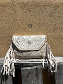 This cowhide and Beige leather bag features fringe sides and can be used as a wristlet or crossbody. It has a geometric print debossed flap with a whipstitch border.  Front View G