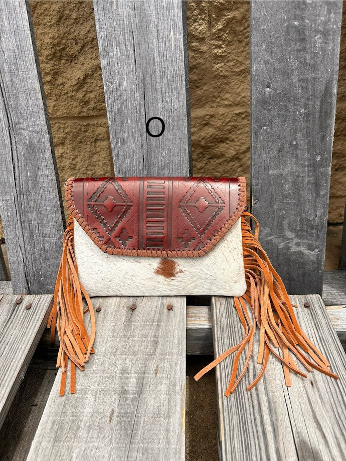 Cowhide purse with Brown leather embossed flap and tassel detail. Has a removable, adjustable shoulder strap and a wristlet strap. Front View O