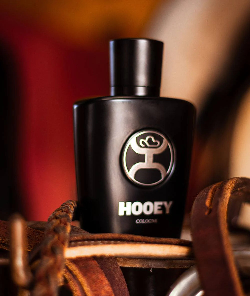 A black bottle of Hooey Men's Black Cologne with a silver logo on the label. Bottle alone