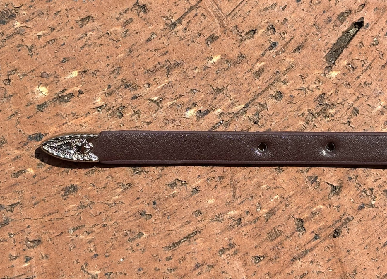 Coffee Brown leather hat band with Horse Head Concho and silver bands separating Conchos. Close up view of end.