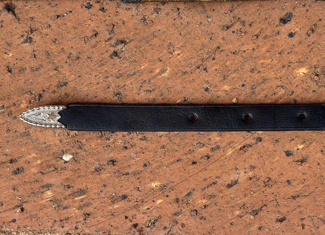 Black leather hat band with a Horse Head Concho with silver bands separating them. This hat band is fully adjustable with a Western style buckle. Close up view of end. 