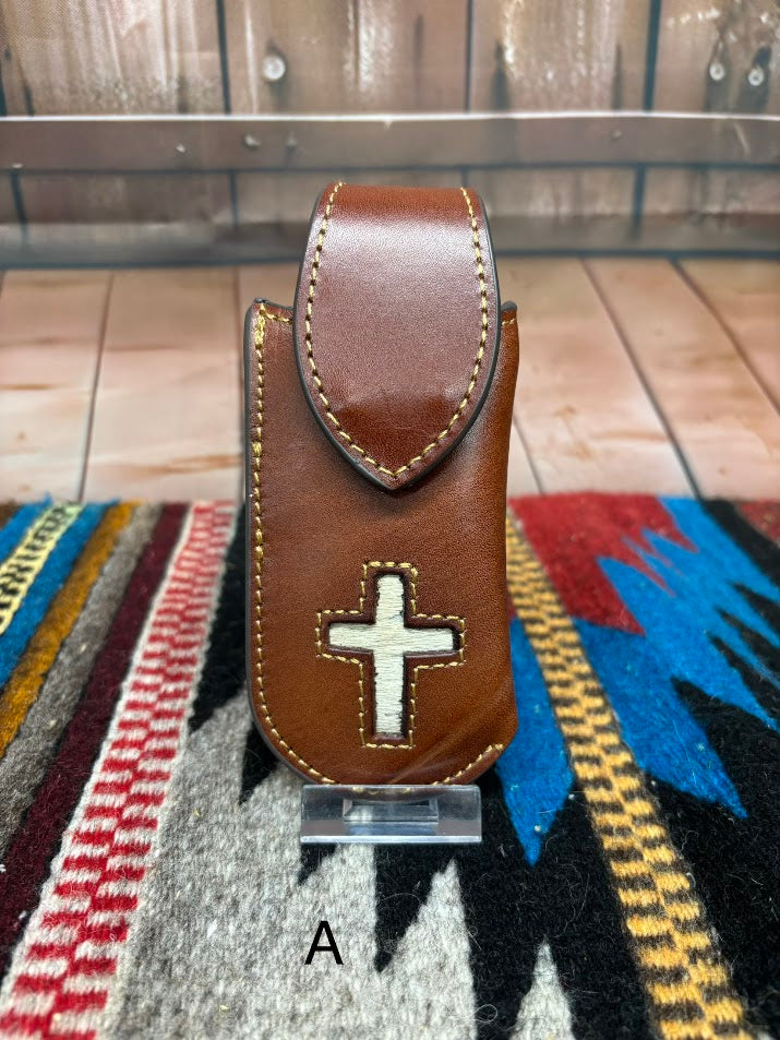 Brown leather knife sheath with a Hair-On cross design.  This sheath features a keep for closure and measures four inches tall and two inches wide. Front View Variant A