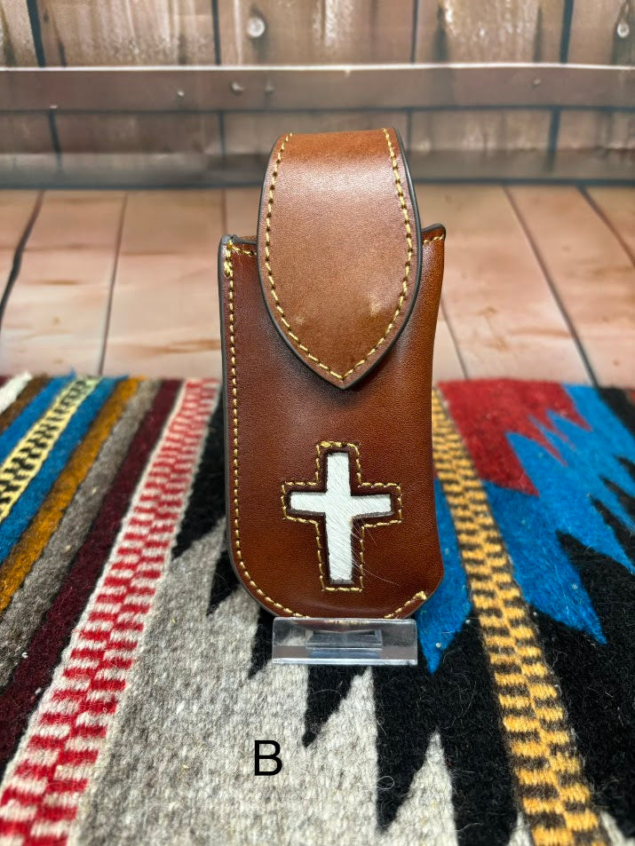 Brown leather knife sheath with a Hair-On cross design.  This sheath features a keep for closure and measures four inches tall and two inches wide. Front View Variant B