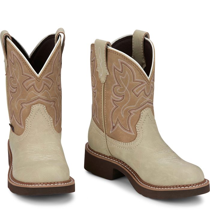 A profile view of a Pair of beige Justin Brand cowboy boots with brown accents on a white background.