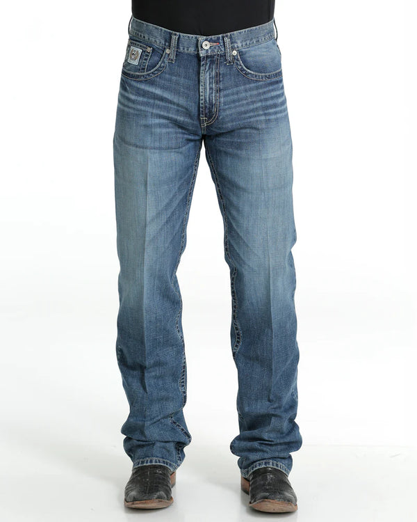 Men's White Label Medium Wash jeans front view showing detail of front pockets and zipper. Also shows relaxed  fit and stack on boots.