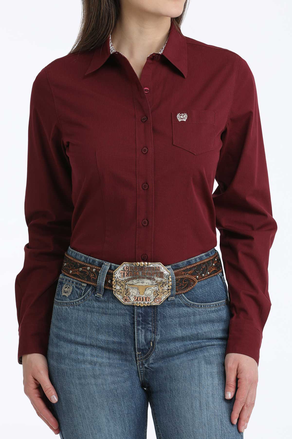 Woman wearing Women's Cinch burgundy print long sleeve button front shirt with a pair of jeans, a western belt and a buckle.