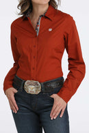 Women's Cinch tailored long sleeve rust red shirt with contrast fabric lining for placket and collar, red buttons, and white embroidered logo on left chest. Front view.