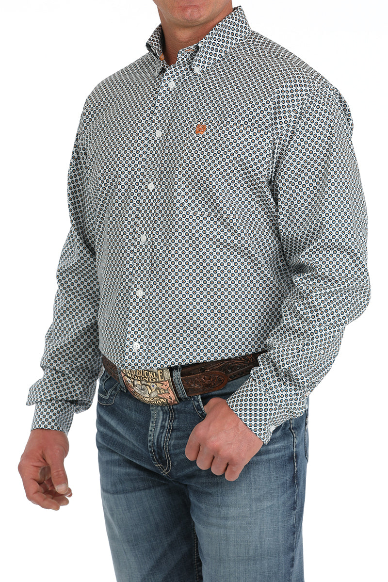 Man wearing a Cinch white print long sleeve button down shirt with left chest pocket and jeans with a belt and buckle. Front angled view.