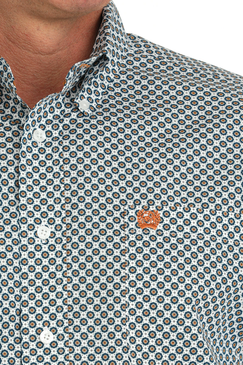 Closeup of a man wearing a Cinch white print button down shirt with left chest pocket with logo embroidery.