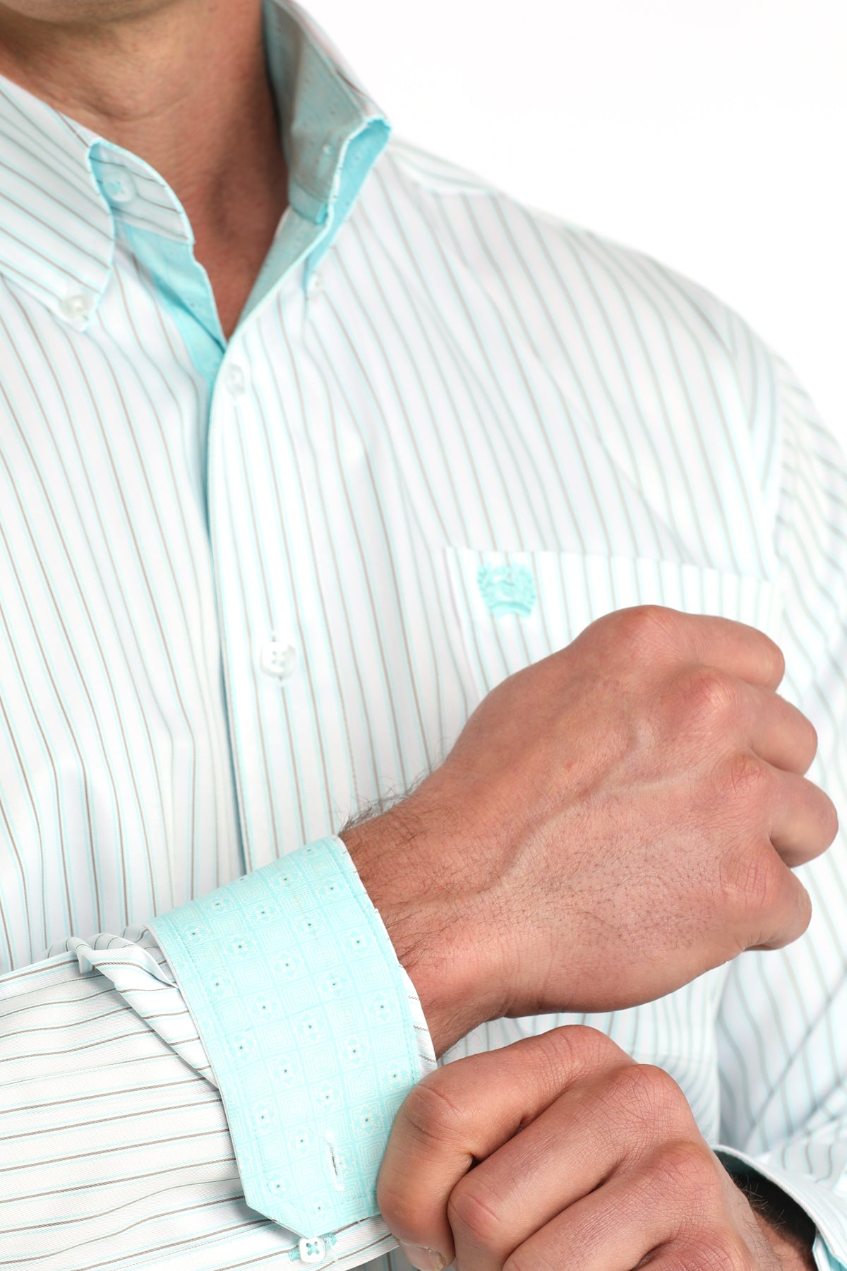 Close-up of a person adjusting the cuff of a light blue and white striped shirt.