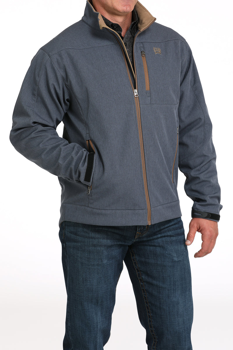 Cinch blue bonded logo jacket with full front zipper in tan with matching lining, velcro adjustable sleeve cuffs, left chest zippered phone pocket in tan, and tan logo embroidered on left chest. Hits mid hip. Front view.