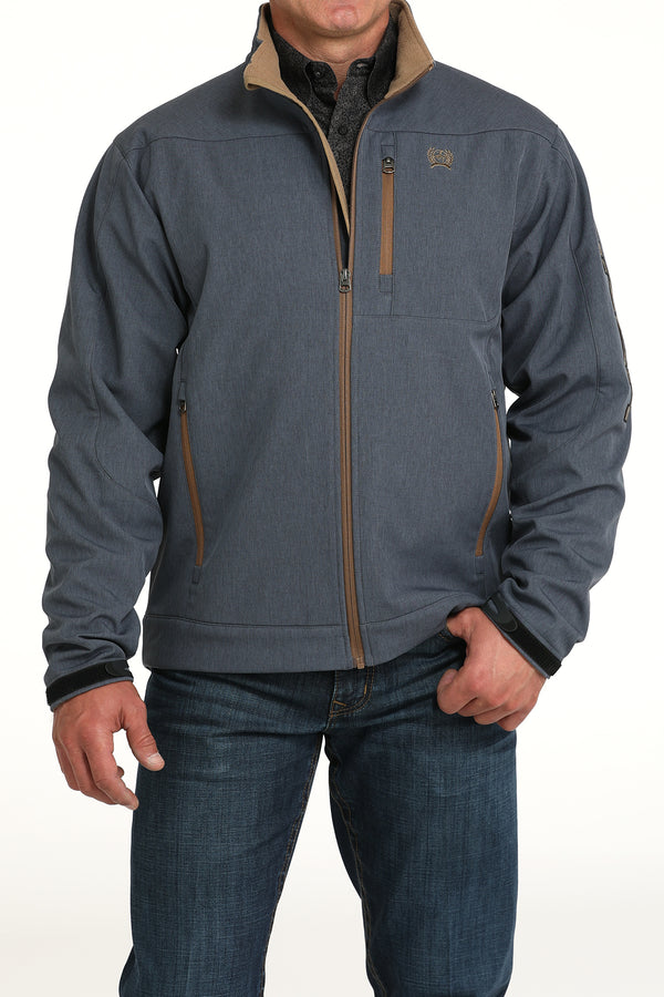 Cinch blue logo jacket with tan velour lined standing collar and zipper, full tan front zipper, 2 tan zippered hand pockets, left chest tan zippered phone pocket, and embroidered tan logo. Hits mid hip. Front view