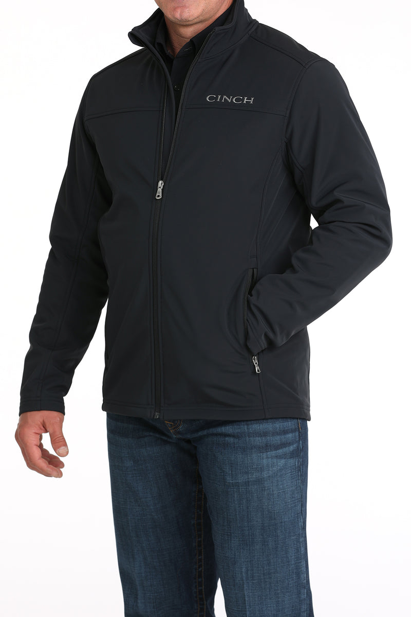 Cinch black solid nylon-spandex ripstop jacket. Has standing collar with soft lining, full front zipper with lining, zippered slash hand pockets, and Cinch block logo embroidered on left chest. Hemmed cuffs and bottom band. Hits low hip. Front left view.