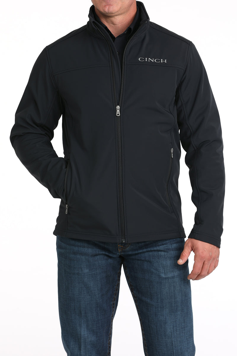 Cinch black solid nylon-spandex ripstop jacket. Has standing collar with soft lining, full front zipper with lining, zippered slash hand pockets, and Cinch block logo embroidered on left chest. Hemmed cuffs and bottom band. Hits low hip. Front view.