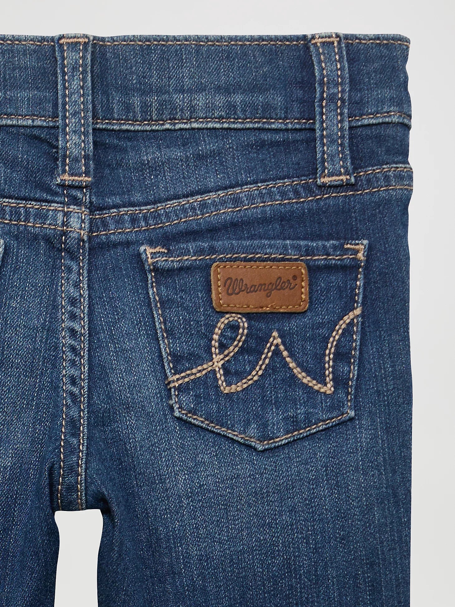 Close-up fiew of back pocket of Wrangler baby girl blue jeans.