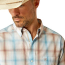 Men's Ariat long sleeve Western style shirt in Light Brown Plaid. Close up of front collar with Ariat shield logo on chest pocket. 