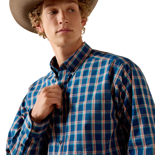 Men's Ariat long sleeve shirt in Poseidon Plaid a blue and red plaid. Front close up view of Ariat shield logo on left chest pocket. 