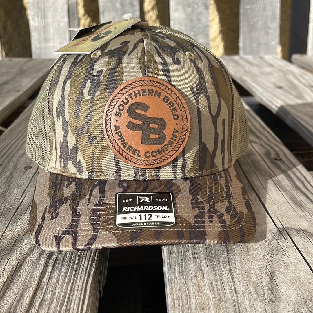 A bottomland camo pattern snapback cap with a leather logo patch on the front featuring the text 'SOUTHERN BRED'.