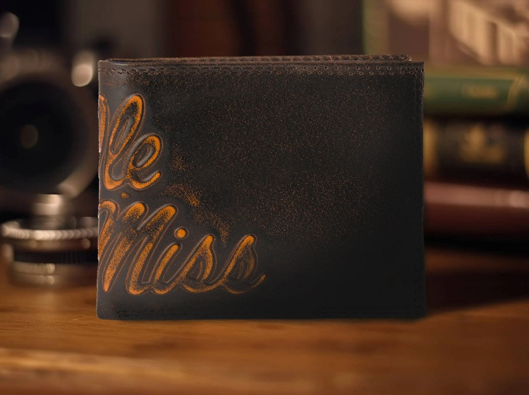 Zep Pro University of Mississippi Ole Miss Burnished Antique Brown Leather Bi-fold Wallet. Front view features script "Ole Miss" logo across spine of wallet.