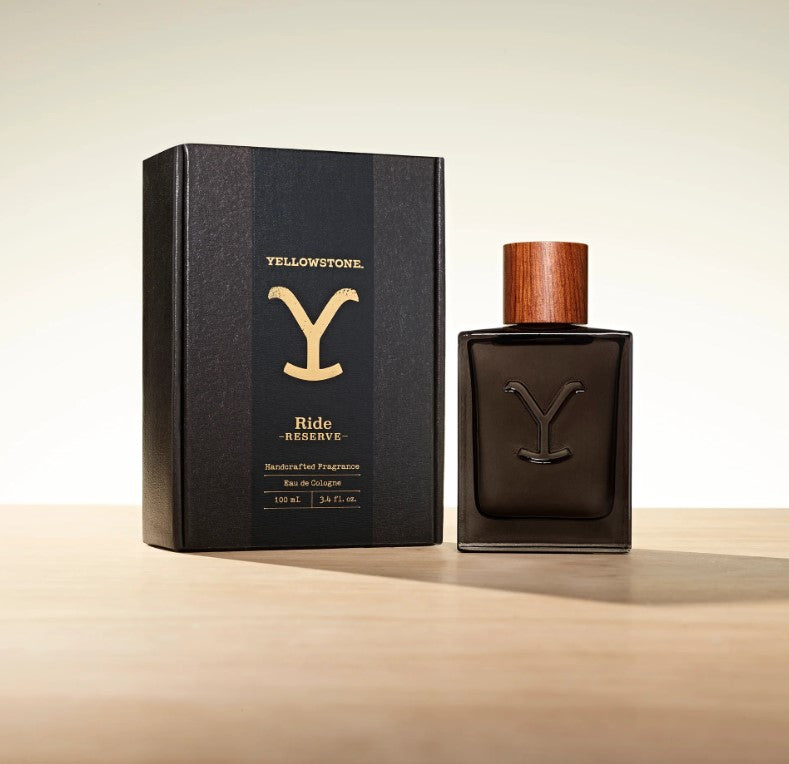 A bottle of Tru Fragrance Yellowstone Ride Reserve Men's Cologne next to its black packaging box with the 'Yellowstone' logo in gold.