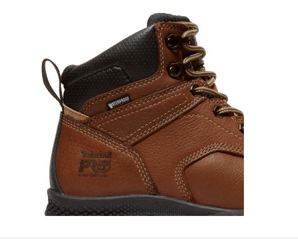 Women's Timberland Brown 6 inch Titan® EV Comp Toe WP Lace-up Boot. Closeup view of side showing stitched reinforcement leather angled up from heel cap to lacing. Also shows back pull strap, reinforced lace holes and top lace hooks.
