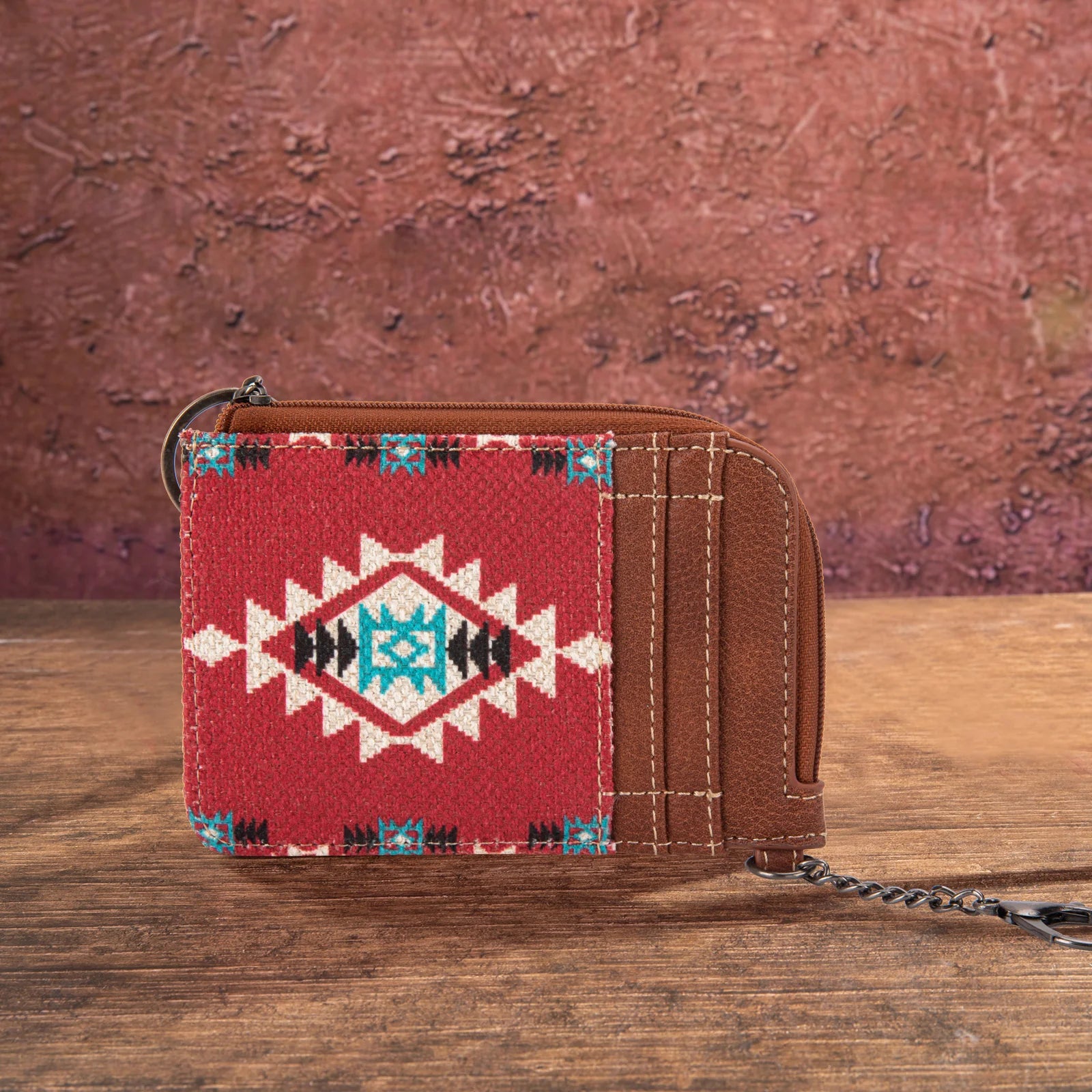 A mini zip card case with a southwestern art print, featuring a geometric pattern in red, white, and blue, combined with a brown canvas body and PU leather accents.