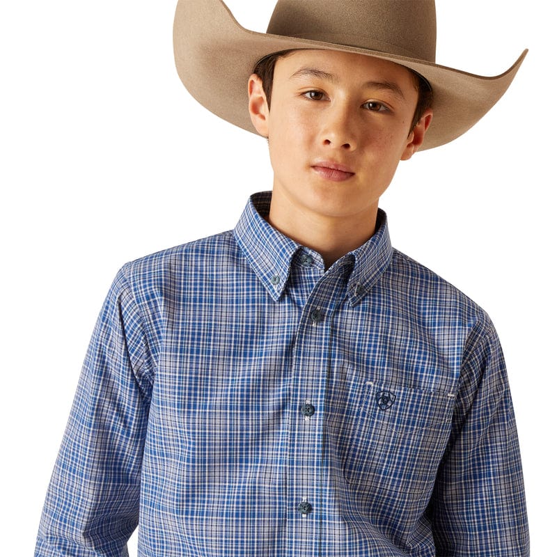 Boy's Ariat long sleeve shirt in True Blue Plaid. Close up of view of front showing button down collar and Ariat shield logo on left chest pocket. 