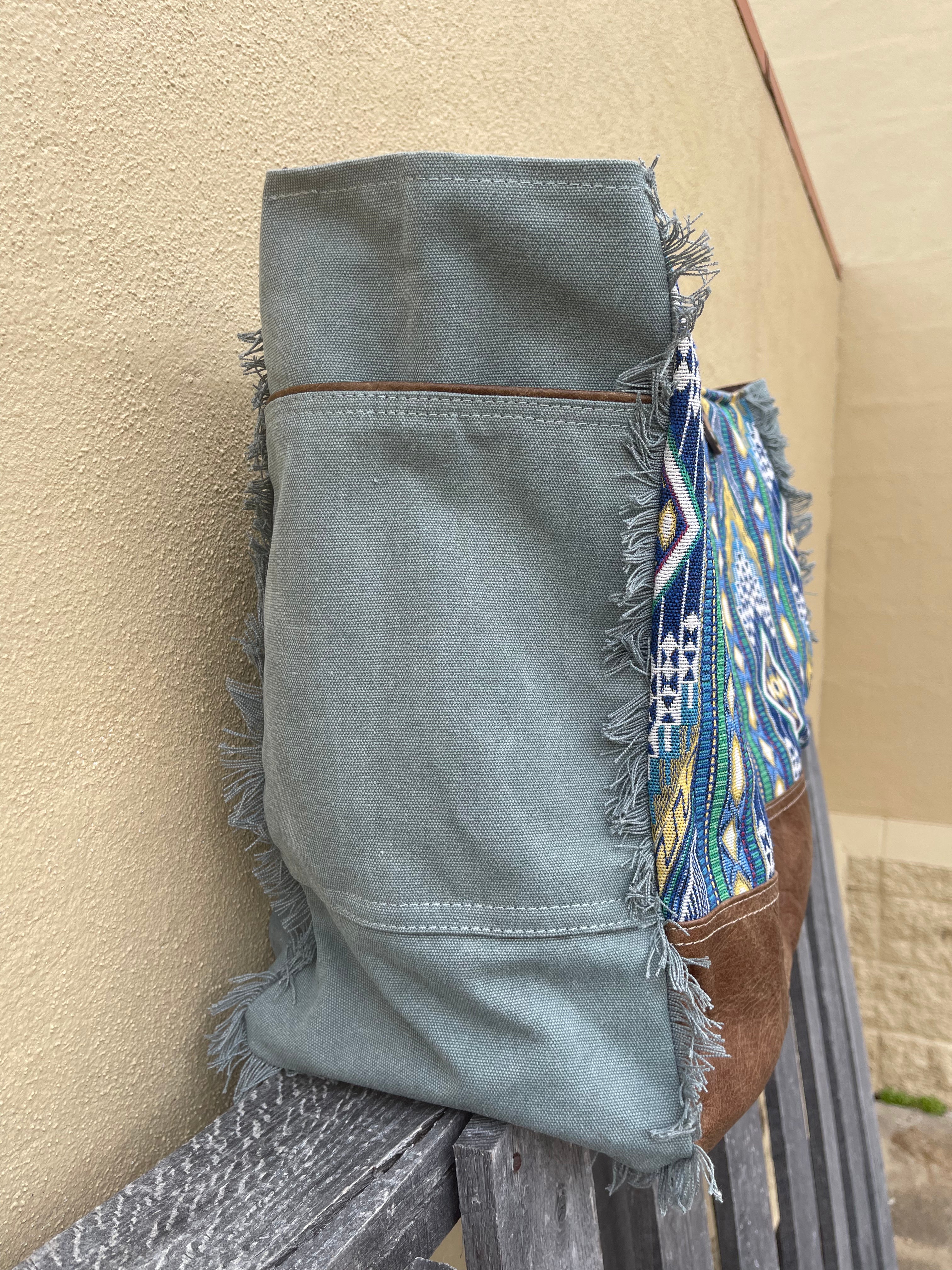 A blue multi canvas and leather conceal carry weekender bag with a geometric pattern. Close up side view showing large pocket. 