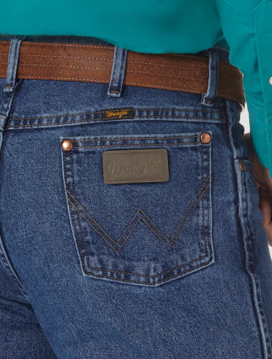 Closeup of a man wearing Wrangler® Cowboy Cut® Slim Fit Stonewashed Jean with a western shirt, and belt. This view shows the  back pocket with the top corner rivets, "W" sitched on each, and a neolite logo patch on the right pocket.. 