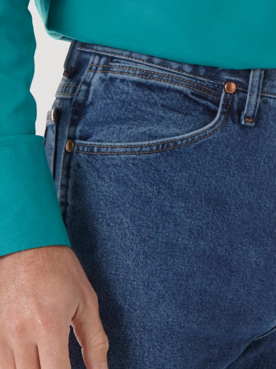 Closeup right front view of a man wearing Wrangler® Cowboy Cut® Slim Fit Stonewashed Jean with a western shirt. This view shows the front scoop pocket with the top corner rivets, the coin pocket, and the belt loop.