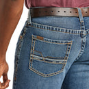 Men's Ariat M5 straight leg jean in a medium wash. Rear view showing stitch details on pocket and Ariat logo tag. 