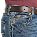 Men's Ariat M5 straight leg jean in a medium wash. Close up view of front pocket showing stitching details and a slanted Ariat logo tag. 