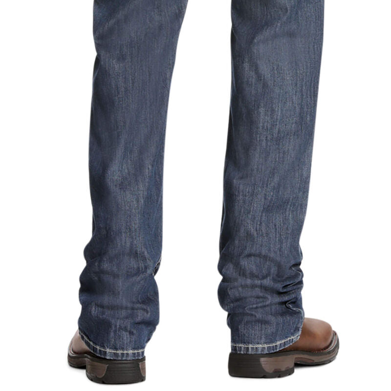 Men's Ariat FR jeans in a M4 relaxed fit boot cut. Bottom view showing leg opening over boots. 