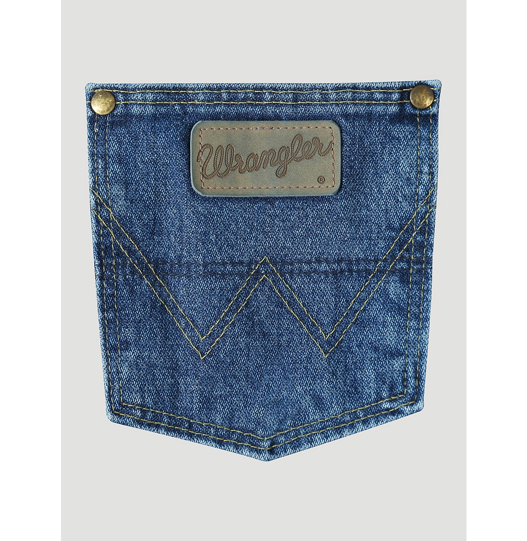A close-up view of the back pocket of a Wrangler men's George Strait Cowboy Cut original fit jeans showing the top rivets, faux leather logo patch, and the "W" stitching.
