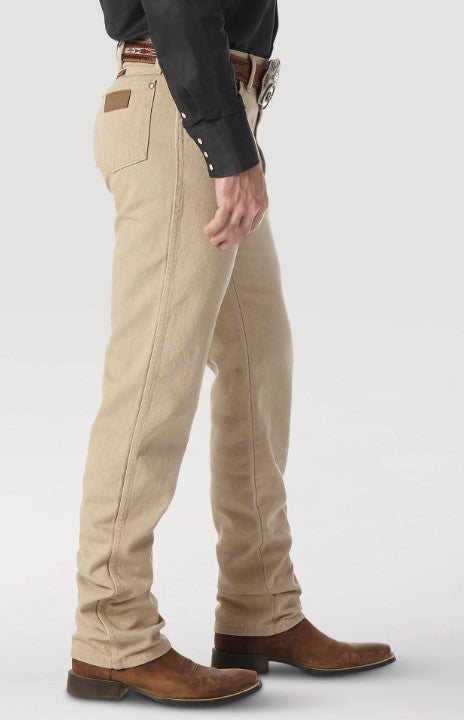 A man wearing Wrangler men's tan prewashed cowboy cut original fit jeans with western shirt, belt, and boots. Side view shows brown neolite patch on right back pocket.