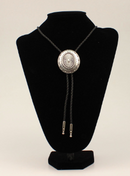 A bolo tie with a silver colored oval western concho slide on a black braided leatherette cord with silver tone tips.