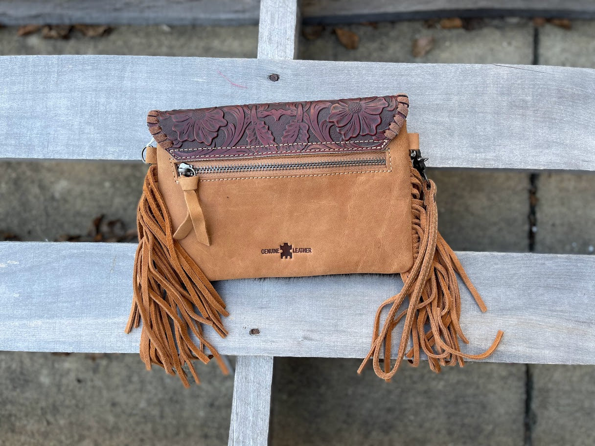 Brown tooled leather and cowhide bag with side fringe. This bag has both a wristlet and should strap. Rear view showing zippered back pocket. 