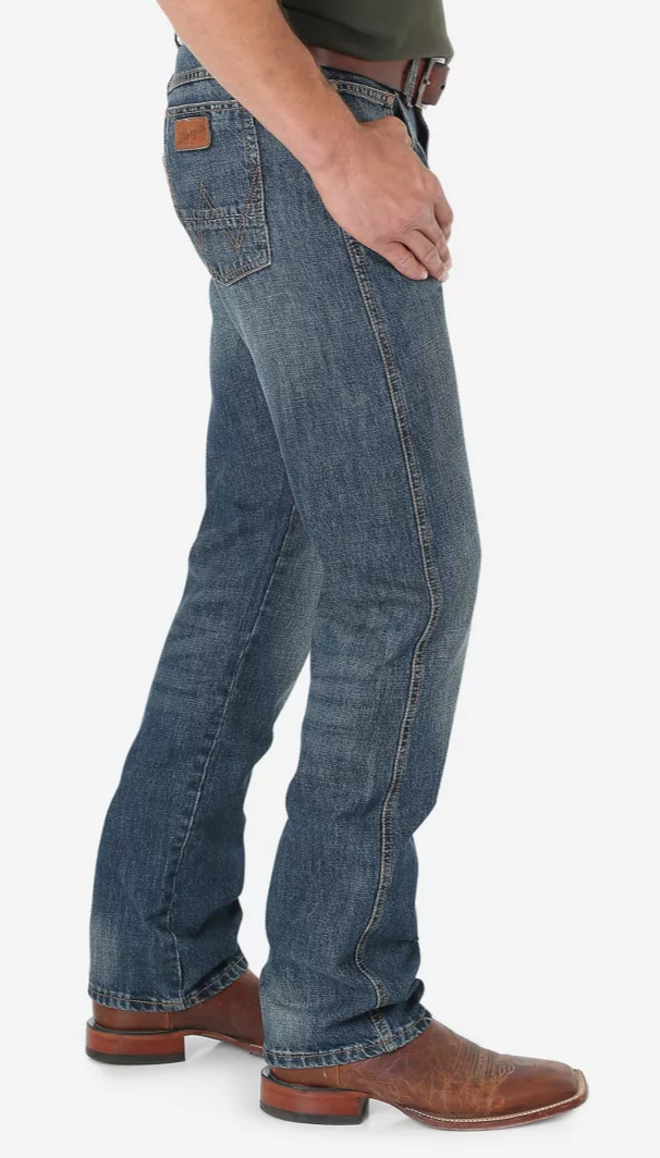 A man wearing Wrangler Retro slim fit straight leg jeans with a dark night wash. Side view.