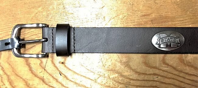 A Zep-Pro brown leather belt laid flat to showa silver metal buckle and an oval M State silver tone concho. 