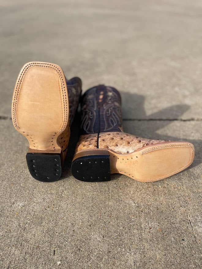 Women's Cowtown boots with a full quill ostrich print leather and square toes, with a 12 inch dark brown shaft with stitching details. Bottom view showing leather outsoles. 