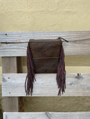 This cowhide and leather crossbody bag has fringe side details and a embossed Turquoise panel along the top front of the bag. Rear view showing solid Brown leather back. 
