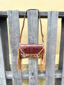 Cowhide purse with Brown leather embossed flap and tassel detail. Has a removable, adjustable shoulder strap and a wristlet strap. Front View E