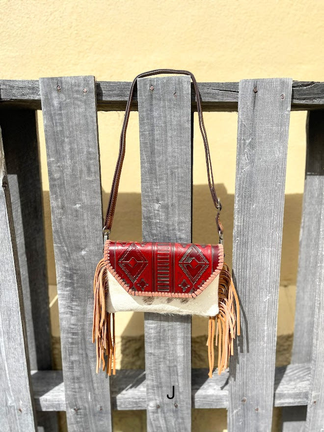 Cowhide purse with Brown leather embossed flap and tassel detail. Has a removable, adjustable shoulder strap and a wristlet strap. Front View J